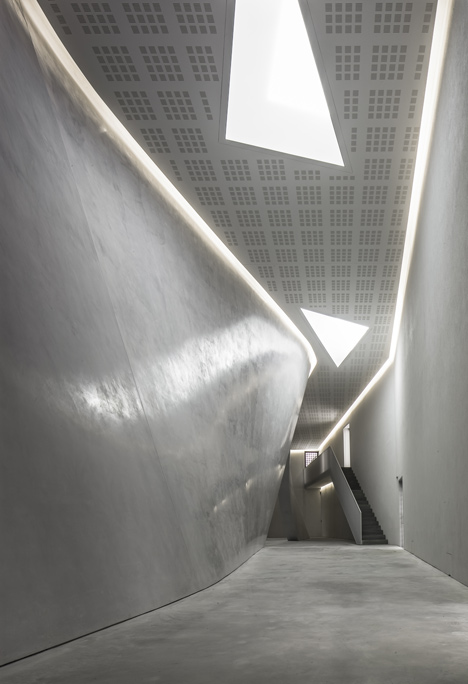 The lobby of the Teatrino, curved concrete under a perforated ceiling. Photography via Dezeen