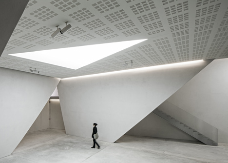 A triangular skylight cut into the perforated ceiling. Photography via Dezeen