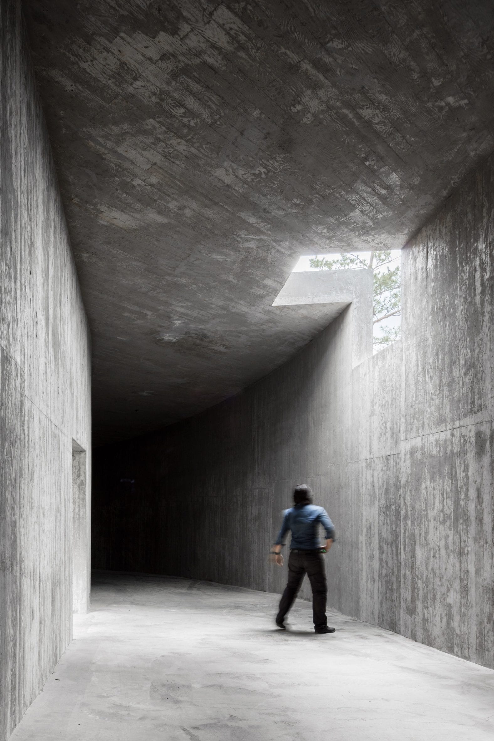 The concrete mass from below the hill, sitting in the trees without apology