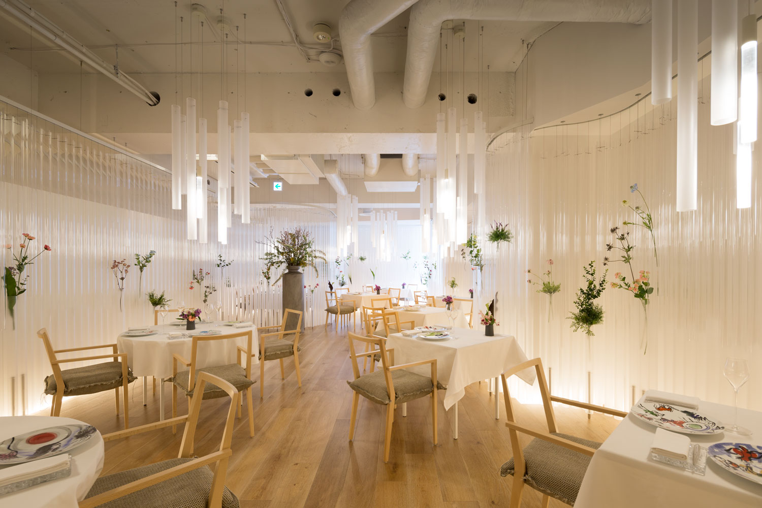 Dining zones framed by the acrylic curtain, with the raw industrial shell painted white behind