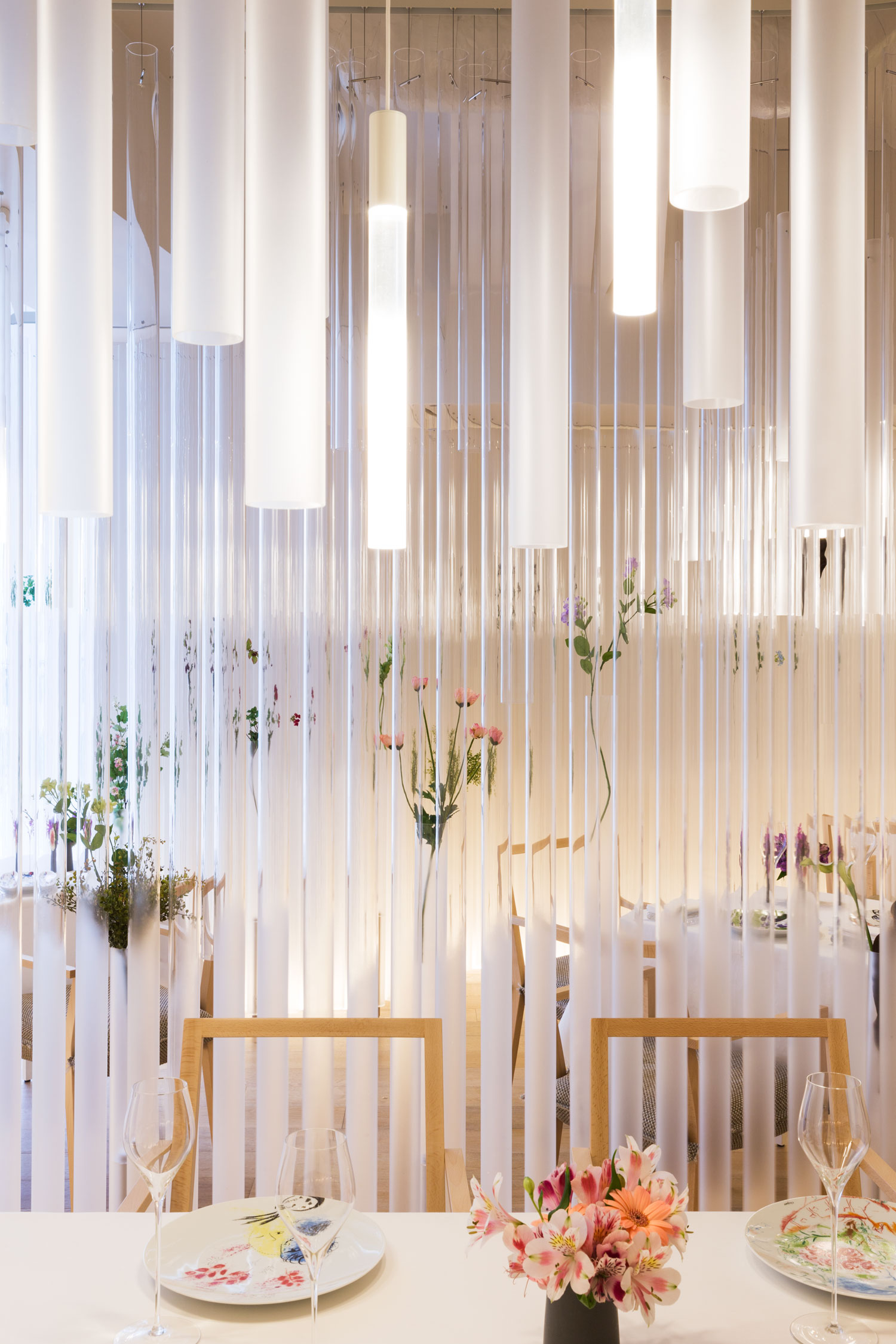 The dining room read through the hanging cylinders, with timber flooring below