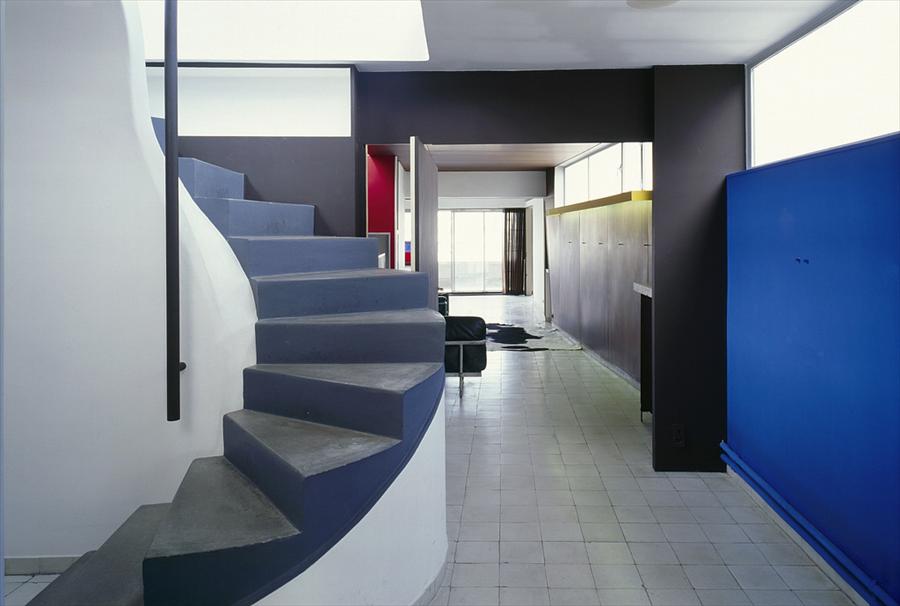 The spiral stair between the two floors, with the blue wall and the tiled floor running under it