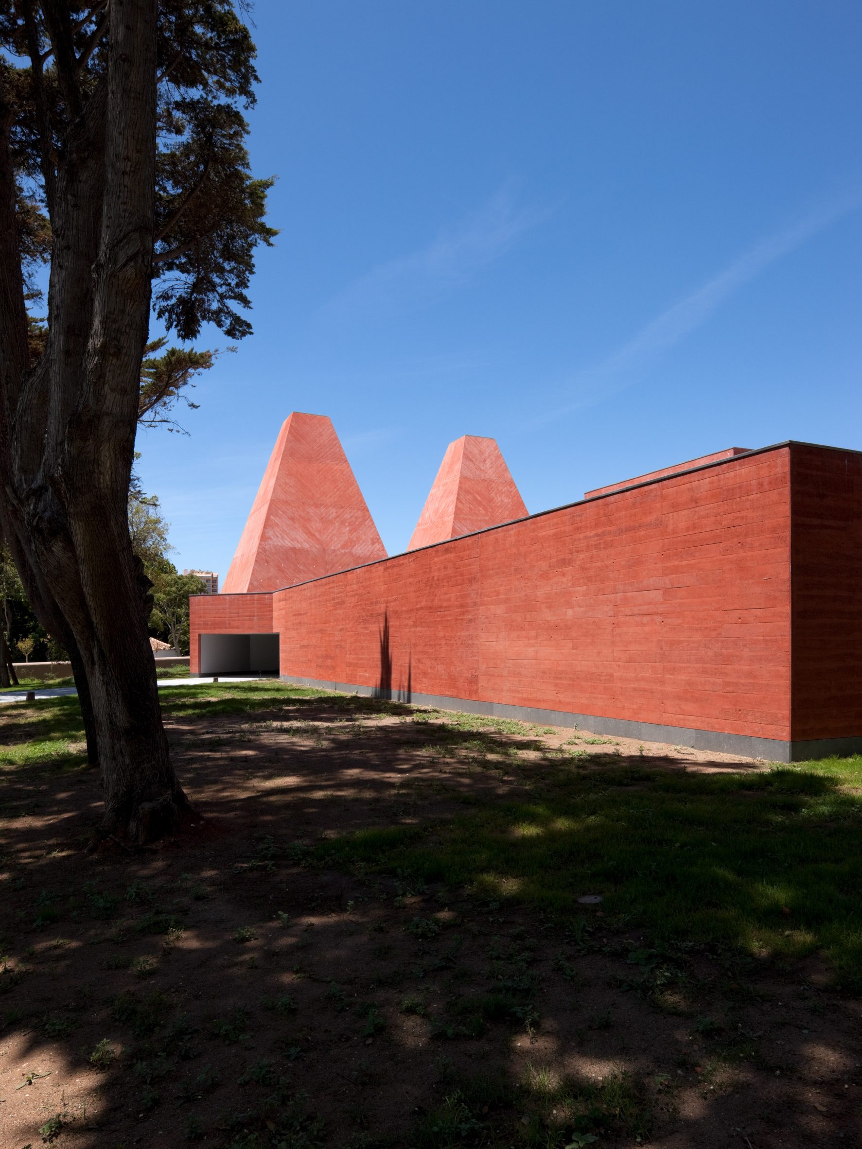 The Casa das Histórias Paula Rego museum in Cascais, Portugal, its pigmented red concrete towers rising above the treeline