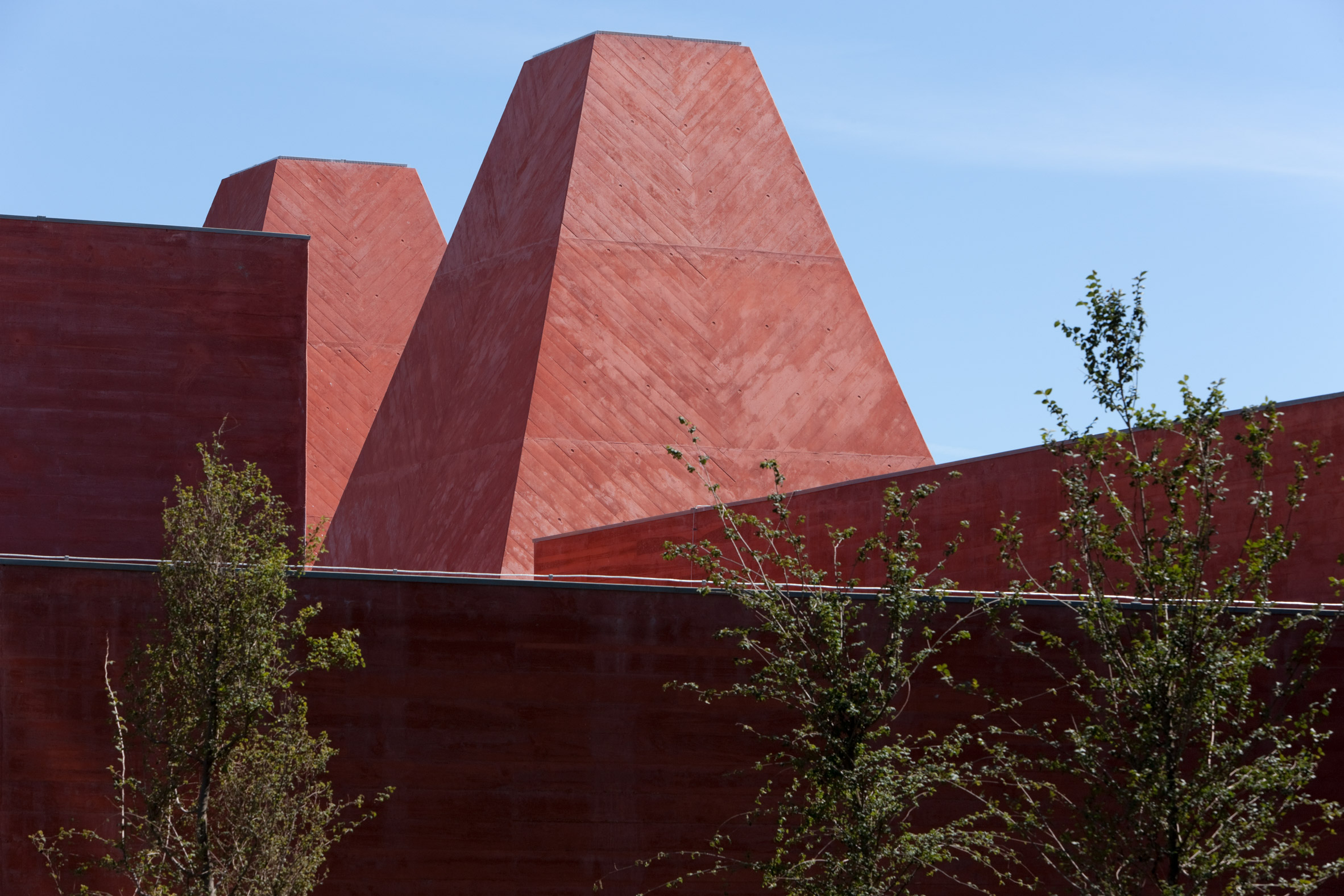 A gallery interior at Casa das Histórias, the red concrete walls meeting a hung Paula Rego work