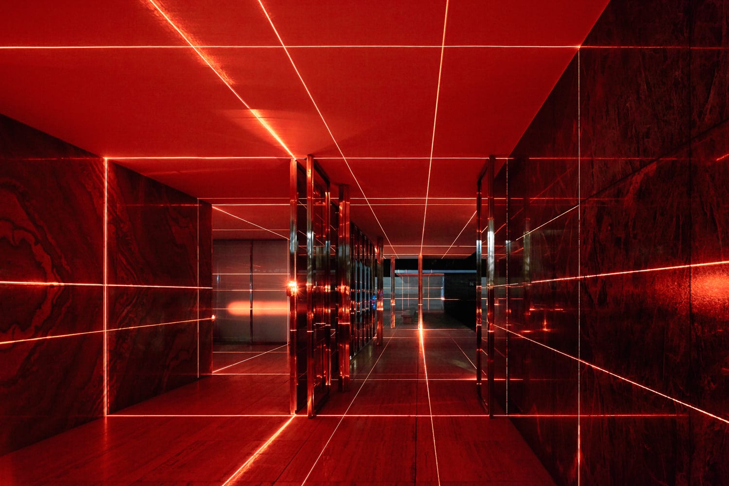 Red laser lines crossing the travertine plinth and the glazed volume of the Barcelona Pavilion