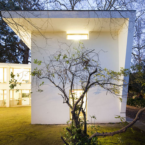 The courtyard side, glazed from floor to roof, with the studios lit at nightfall