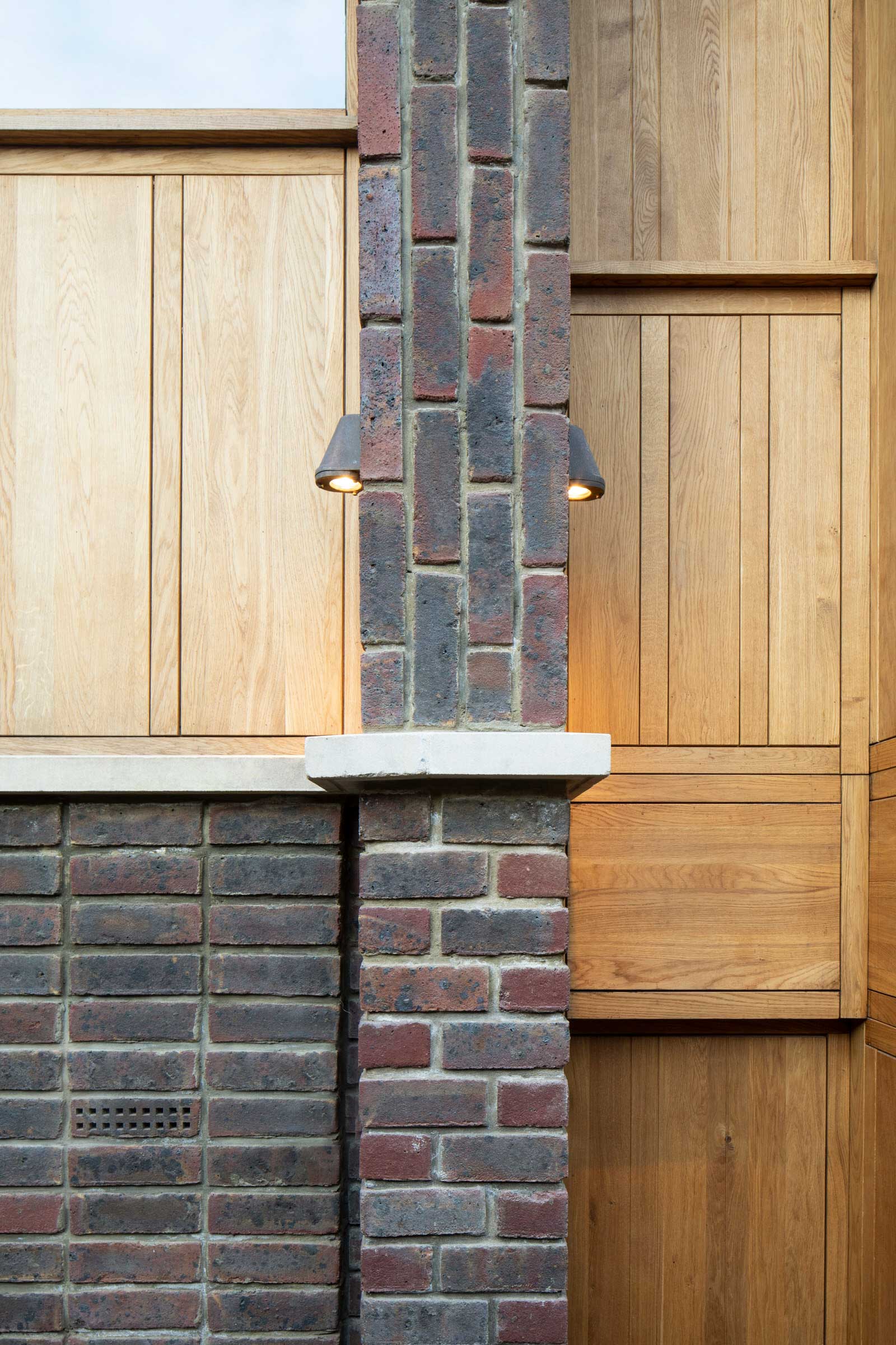 Glass stair between masonry walls, lit from geometric skylights above